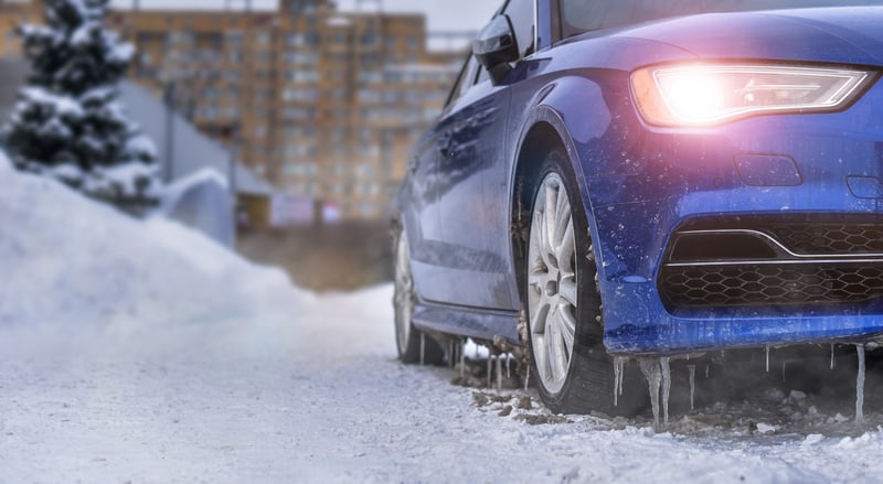 一辆蓝色的汽车在冬天被冰雪怠速预热