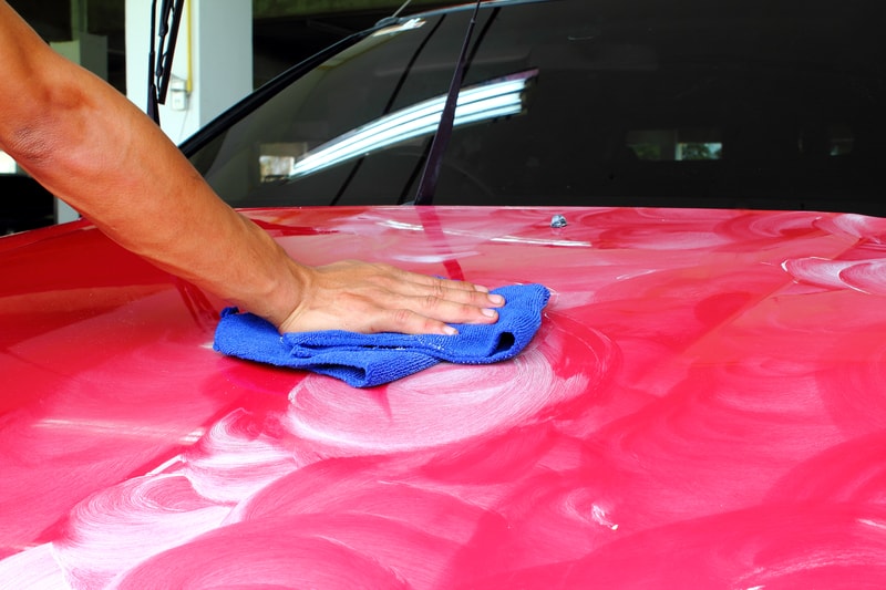 一名男子详细介绍了一辆红色汽车的抛光和在清漆上涂蜡以保护汽车