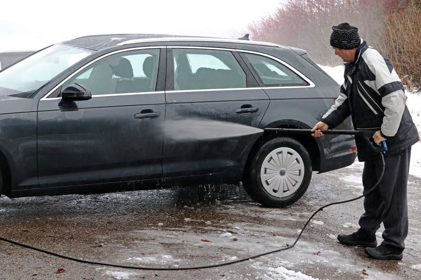 一个男人在冬天用高压清洗机洗车
