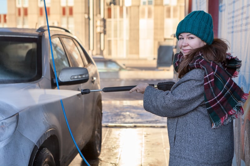 一个女人在冬天用温水压力喷射洗车