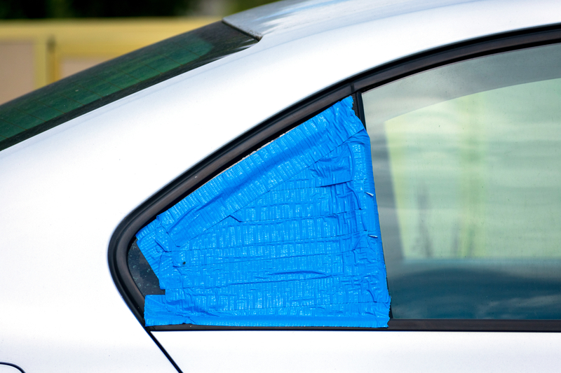 暂时用蓝色胶带覆盖的汽车破窗，以保护内部免受雨水侵袭