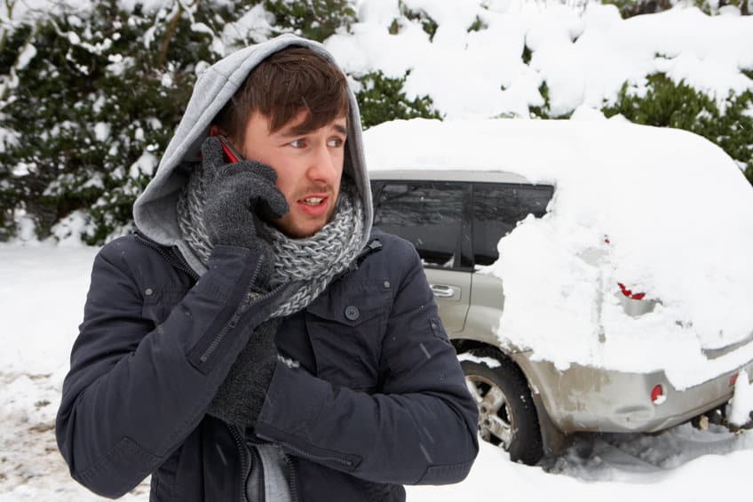 雪中​​的年轻人与损坏的汽车