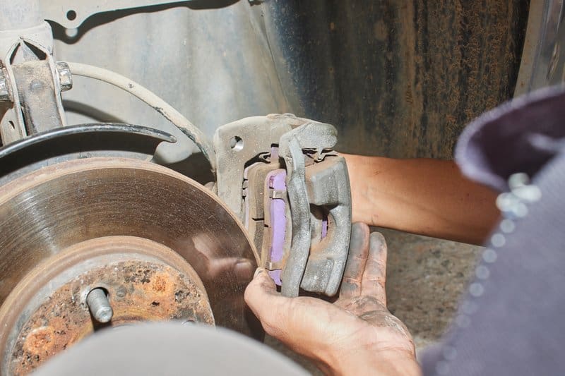 汽车修理工从转子上拆下带刹车片的刹车卡钳