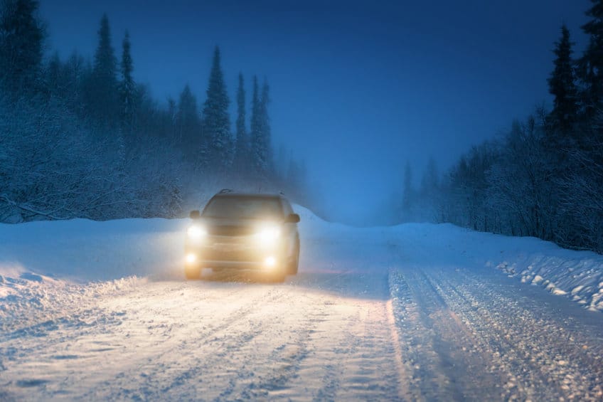 夜间开大灯的汽车在冬天的雪路上行驶