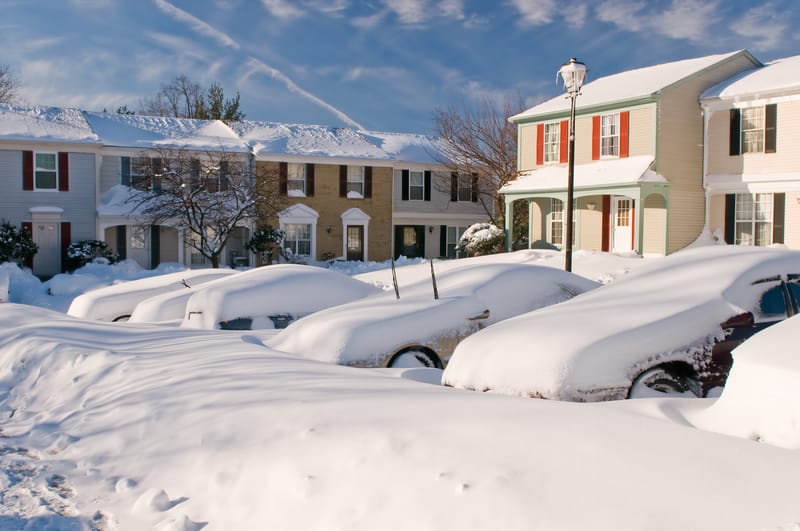 暴风雪过后，房屋旁边的汽车被雪覆盖