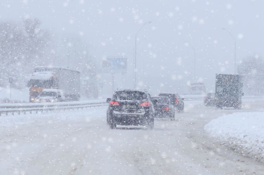 冬天白天在雪天和结冰的道路上行驶的高速公路上的汽车