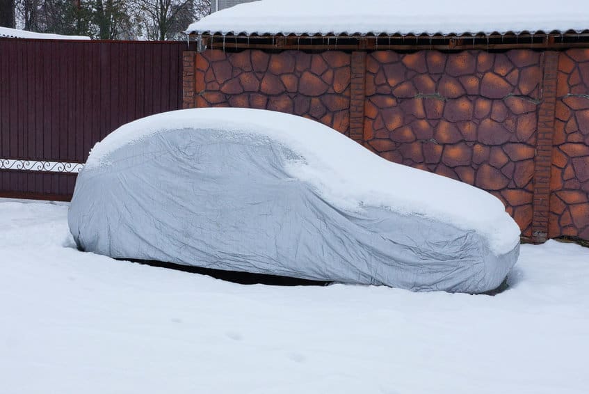 冬天从冰雪覆盖汽车的灰色灰色汽车罩篷布