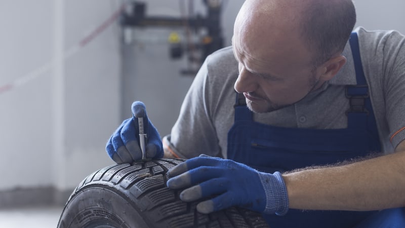 机械师用轮胎花纹深度计检查轮胎花纹深度和磨损