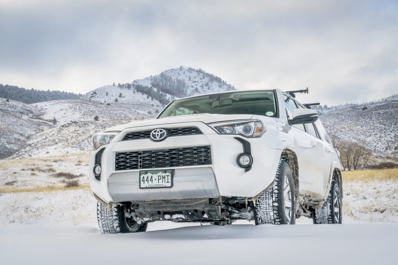 白雪皑皑的土路上的白色丰田 4Runner SUV