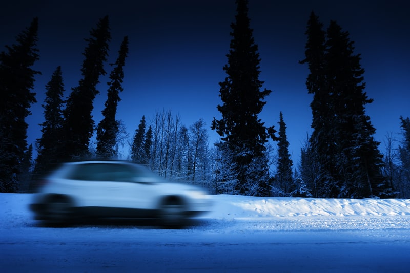 冬天，在孤独的白雪覆盖的道路上行驶，带大灯的白色汽车